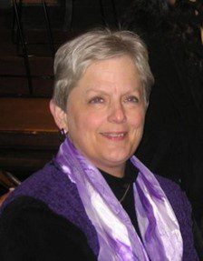 A woman wearing a purple scarf and sitting in a church.