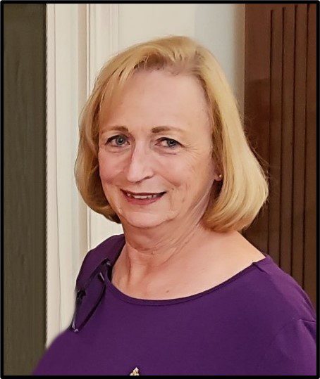 A woman in a purple shirt smiles for the camera.