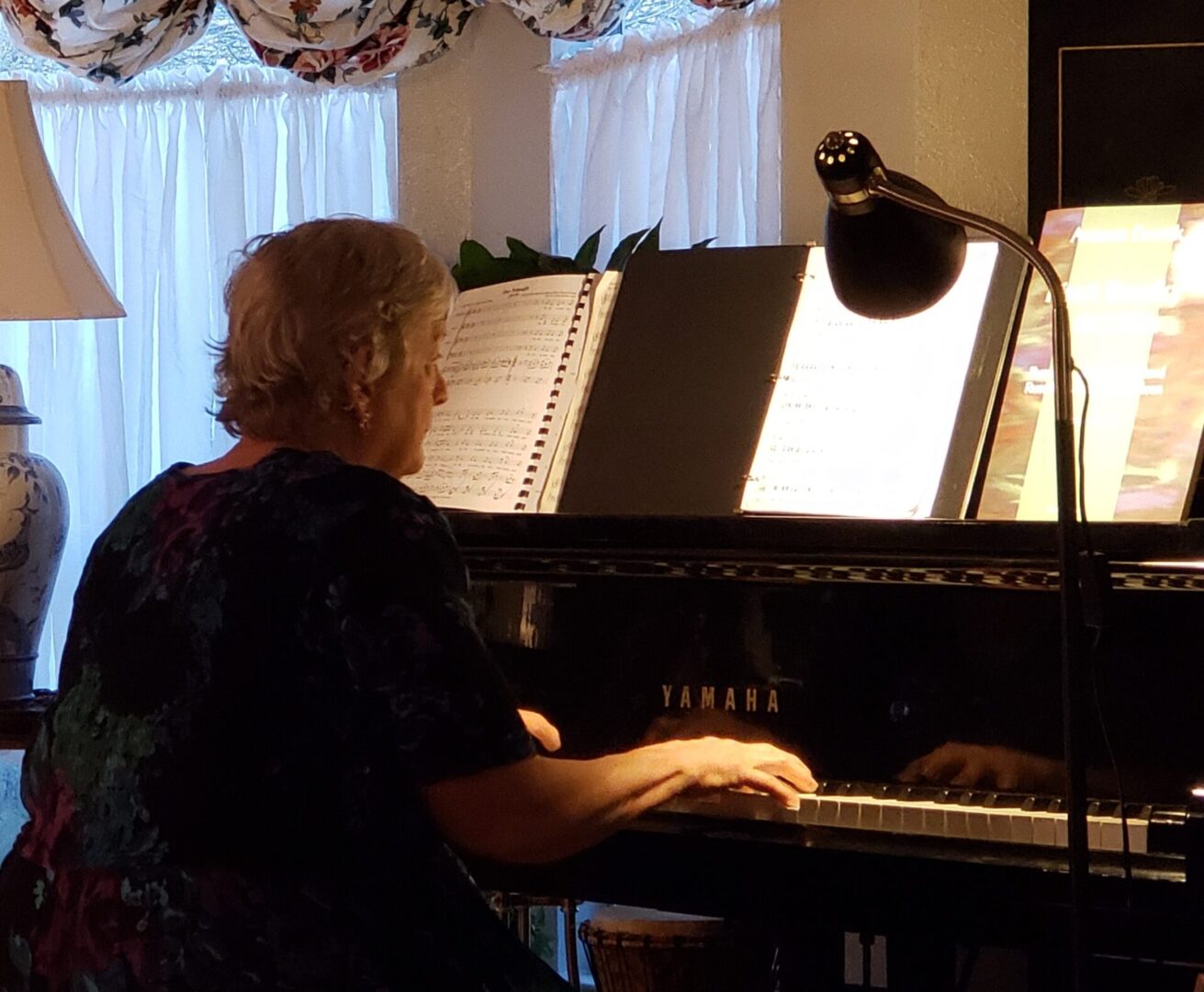 A woman playing a piano in a living room.