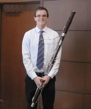 A man holding a clarinet in front of a door.