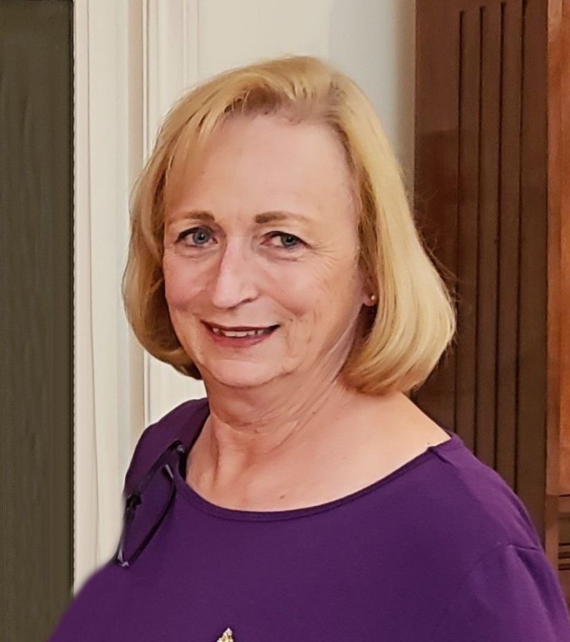 A woman in a purple shirt standing in a room.