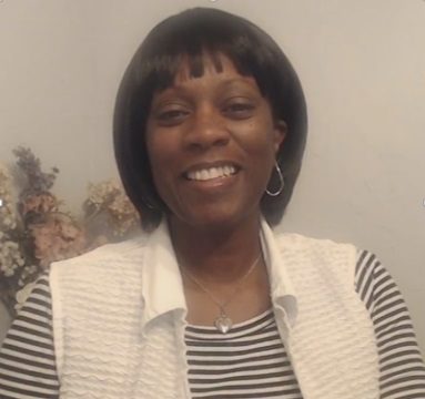 A woman wearing a white shirt and striped vest.