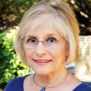 An older woman wearing glasses and a blue top.