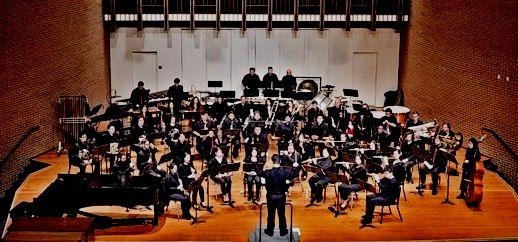 Symphony orchestra performing in a large auditorium.