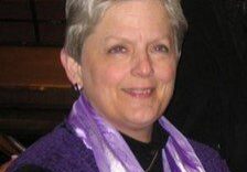 A woman wearing a purple scarf and sitting in a church.